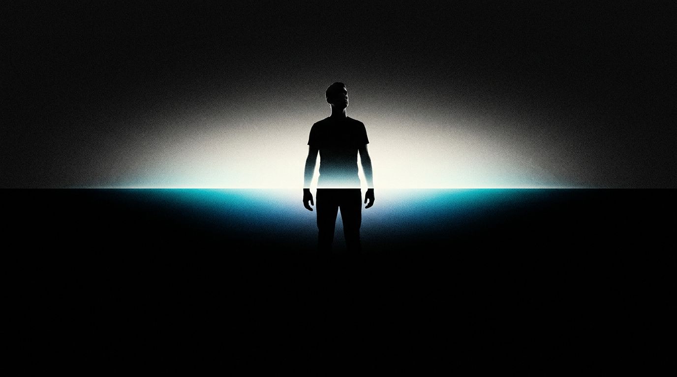 A silhouetted figure stands centered with the upper half clearly illuminated against a bright horizontal line of cyan light, while the lower half from the waist down dissolves into pure black void